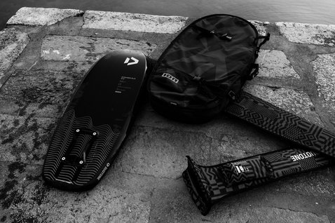 ION Pump Foil Boardbag Tec 3'4'' in black on a stone dock with Duotone foil board