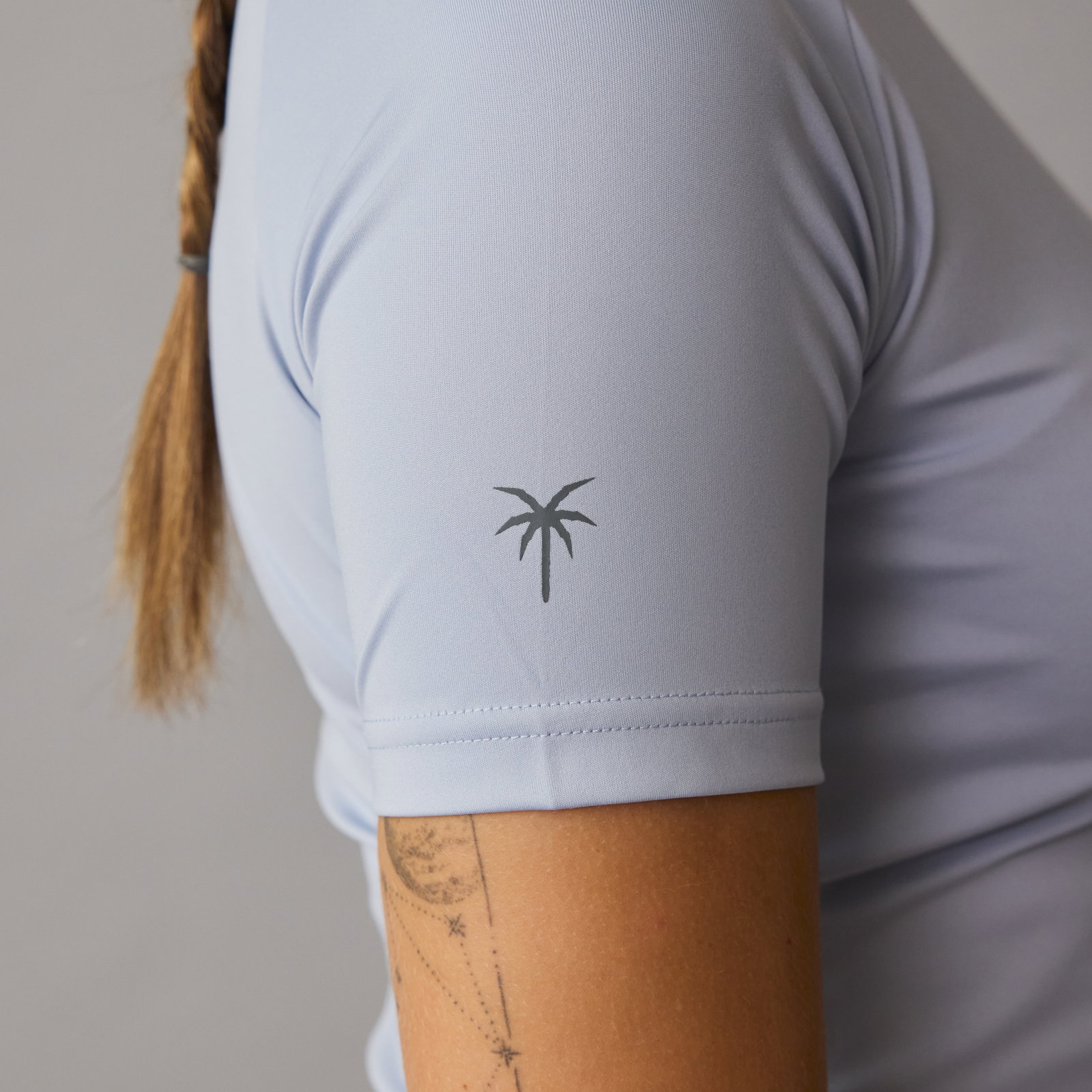 ION short-sleeve rashguard women in mist blue — sleeve detail with palm tree logo