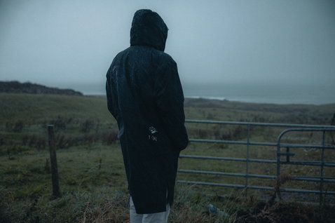 ION Water Jacket Storm Coat unisex in tiefschwarz beim Tragen an der regnerischen Küste