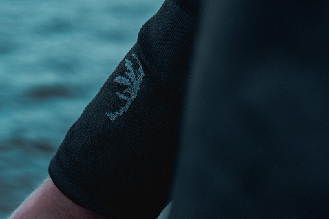 ION Surf Shield rashguard manica lunga unisex in nero dettaglio manica con logo ION sull'oceano