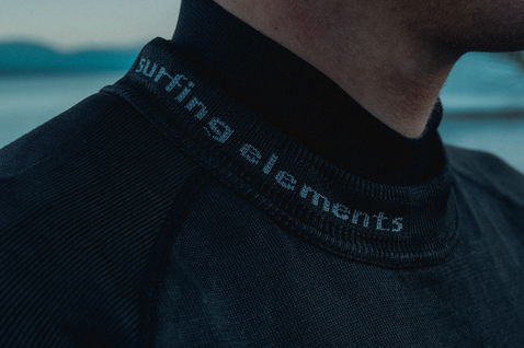 ION Surf Shield rashguard unisex a maniche lunghe in nero, dettaglio collo con scritta 'surfing elements'