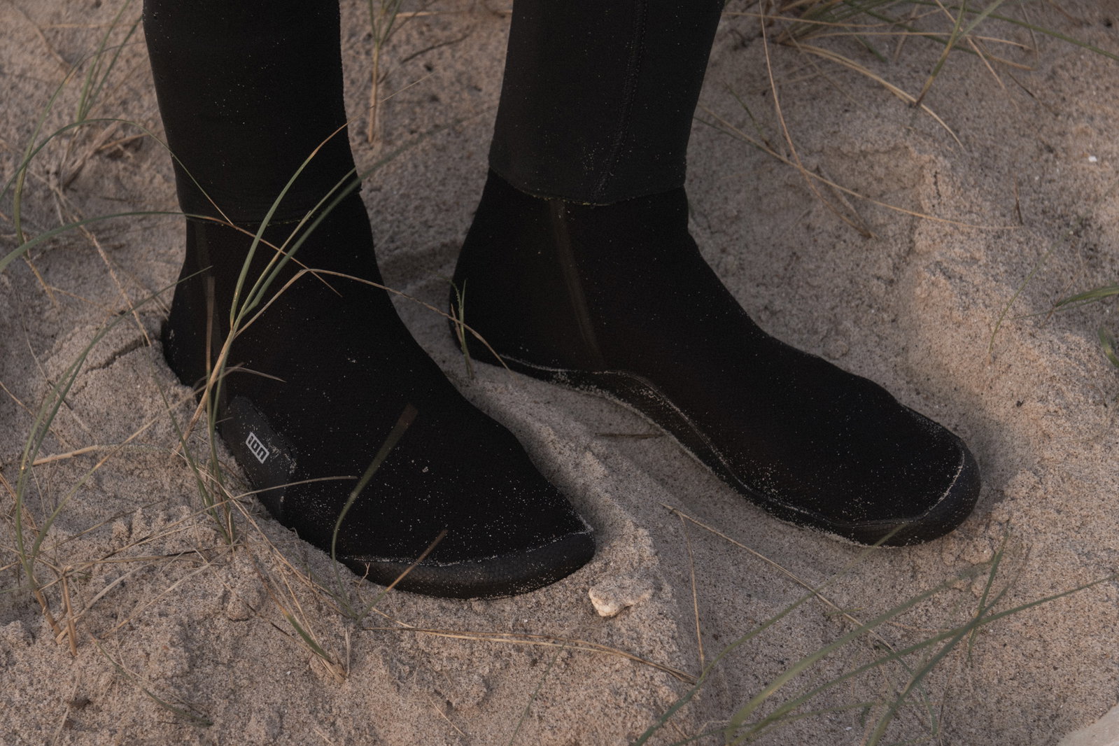 ION Ballistic Socks 3/2mm round-toe neoprene socks in black during kitesurfing on the beach