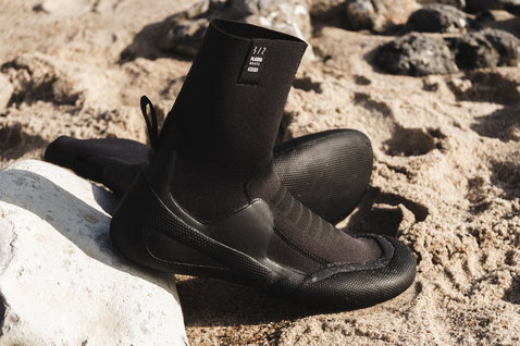 ION Plasma Boots 6/5mm round toe neoprene boots in black on a sandy rocky beach