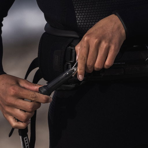 Detailed shot of a kiter securing the leash to the harness, highlighting a reliable and secure connection.