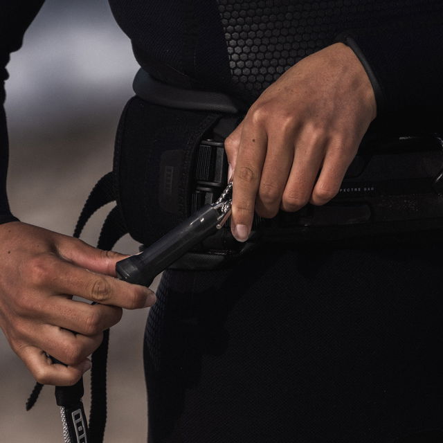 Detailed shot of a kiter securing the leash to the harness, highlighting a reliable and secure connection.