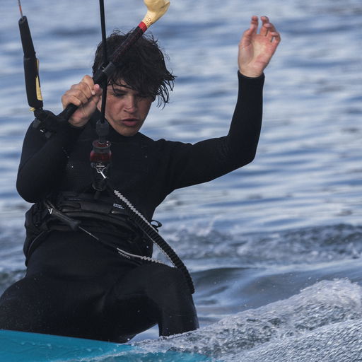 Kiter riding across the water with the leash clearly visible in front — action shot highlighting safety and control.