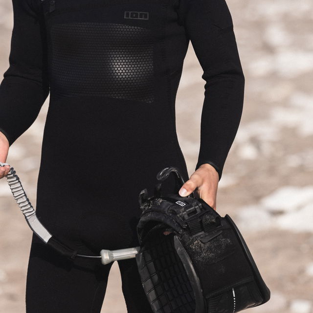 Kiter holding the leash carabiner in one hand and the harness in the other — close-up of connecting the gear.