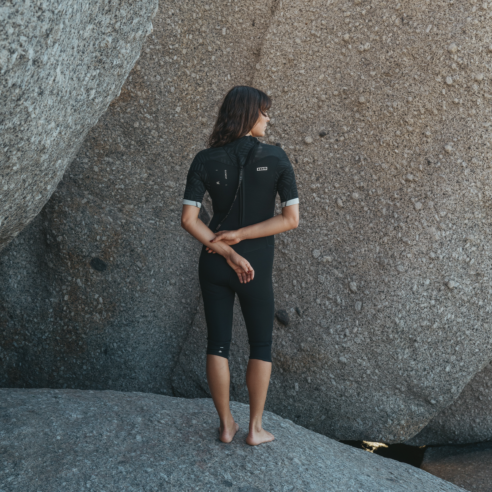 ION Element 3/2mm Kurzarm Overknee Backzip Neoprenanzug Damen in schwarz beim Tragen an der Küste