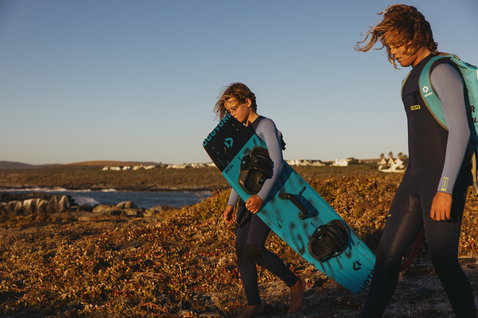 ION Capture 4/3mm Frontzip-Neoprenanzug Junior in dunkelgrau und petrol beim Kitesurfen an der Küste
