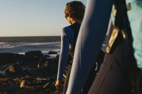 ION Capture 5/4mm Frontzip Junior Neoprenanzug in schwarz und stahlblau beim Surfen an der Küste