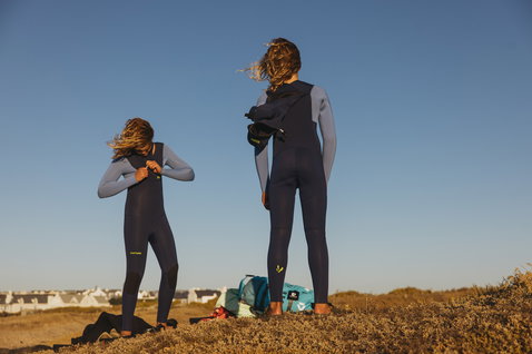 ION Capture 6/5mm Front-Zip Fullsuit mit Kapuze Junior beim Surfen an der Küste in dunkelblau und stahlblau