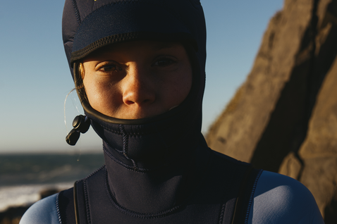 ION Capture 6/5mm Kapuzen-Front-Zip Neoprenanzug Junior in dunkelblau beim Surfen an der Küste
