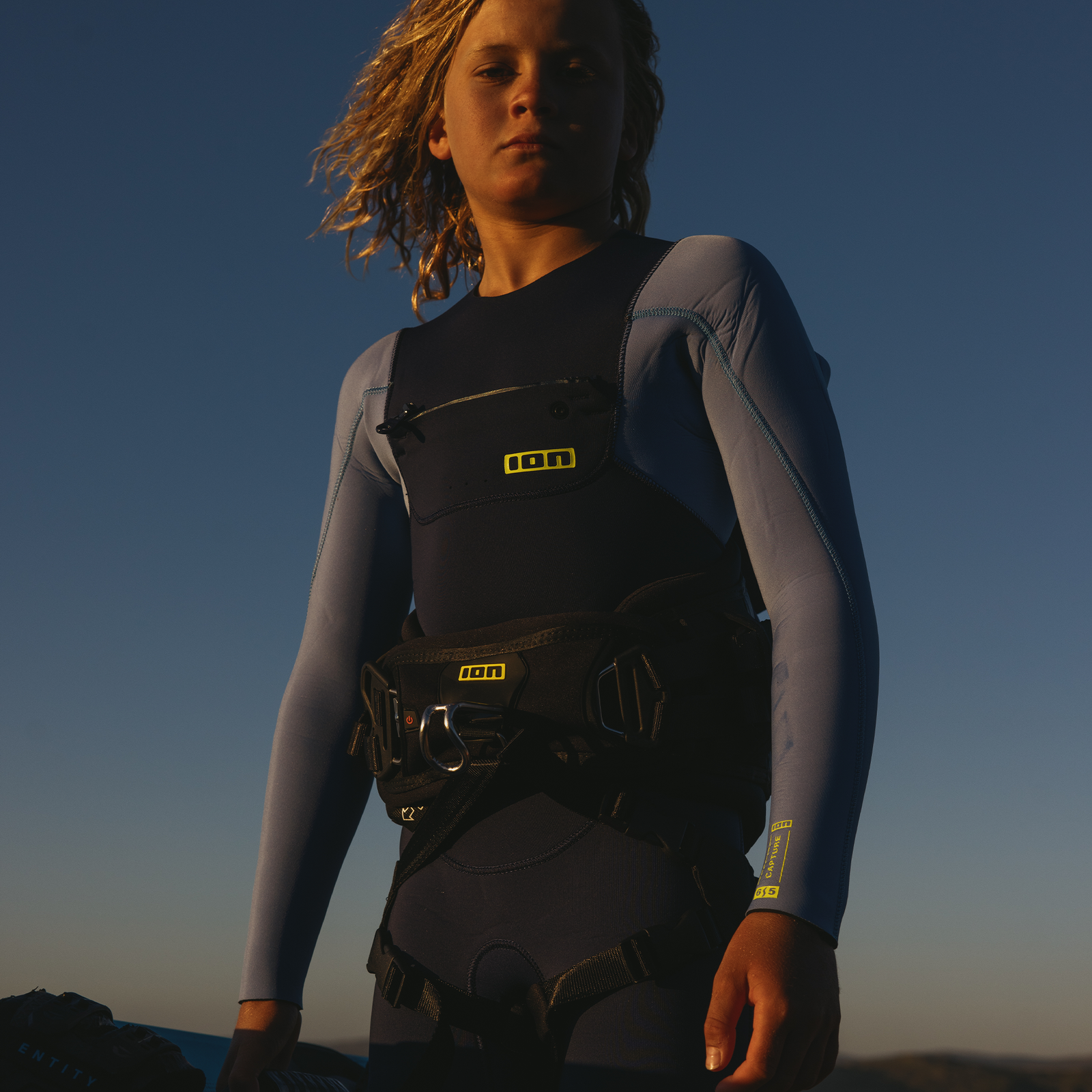 ION Ripper Kinder-Hüfttrapez in schwarz mit neongelben Akzenten beim Kitesurfen an der Küste