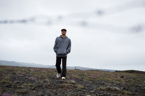 ION Water Hoody Surfing Elements men's hoodie in washed blue worn outdoors on a rocky highland terrain