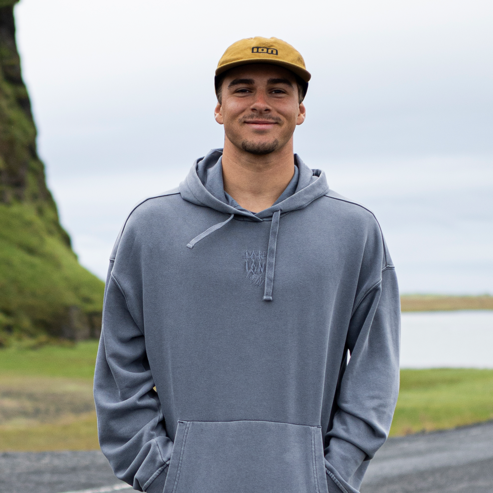 ION Session cap in mustard yellow worn by a man at a coastal outdoor location