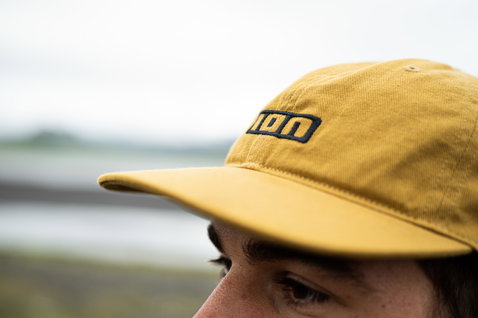 ION Session cotton cap onesize in mustard yellow with navy embroidered logo at the coast