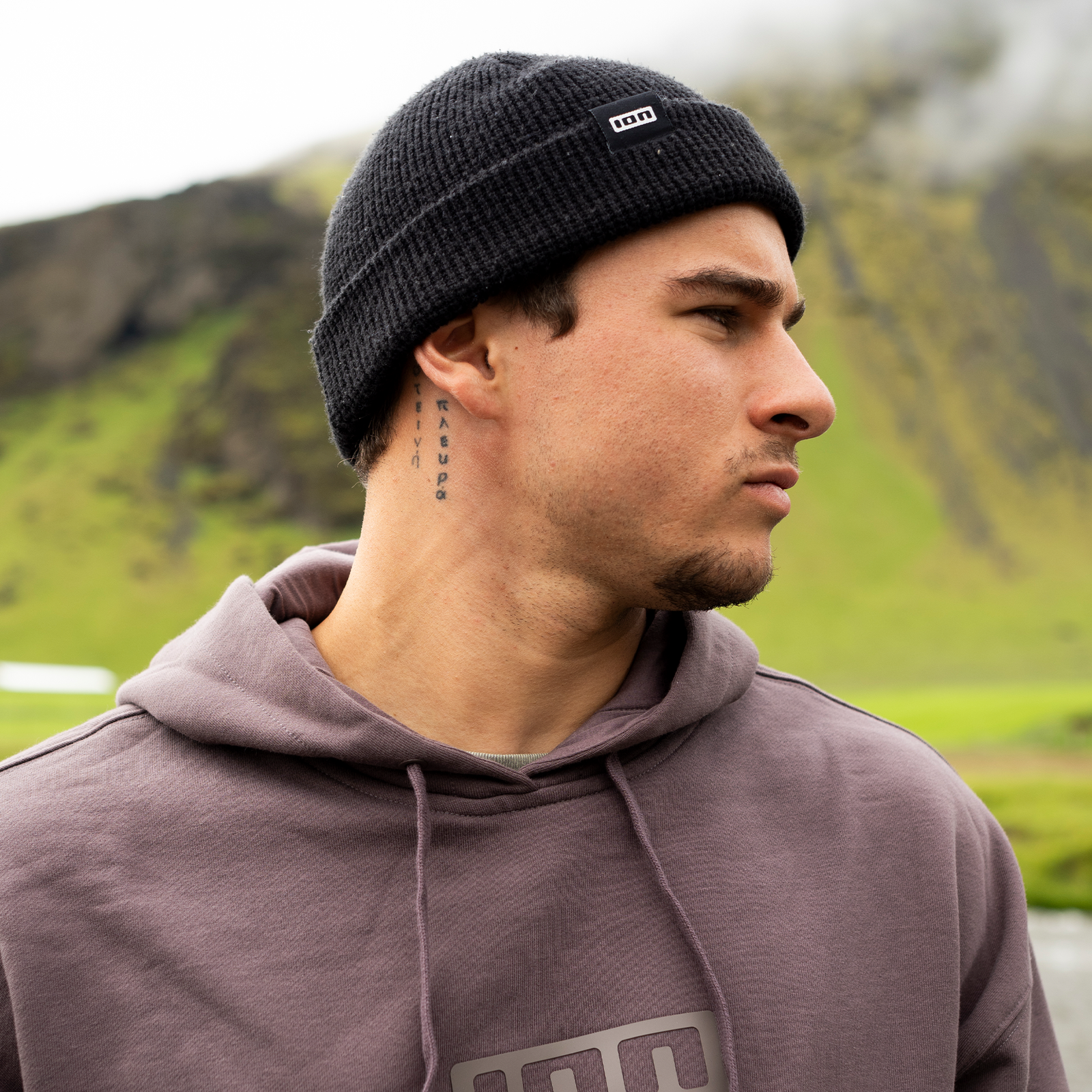 ION Ionic roll-up beanie in charcoal black worn on model in mountain landscape