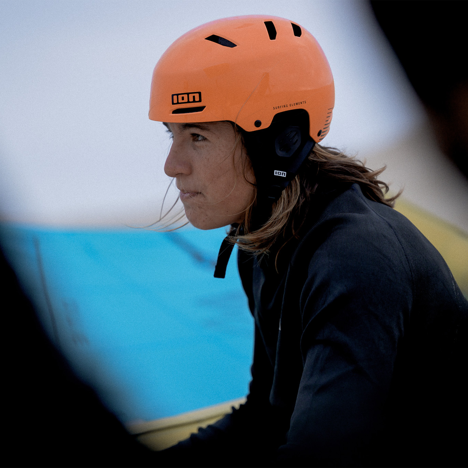 ION Slash Amp helmet during kitesurfing in bold orange with integrated ear pads