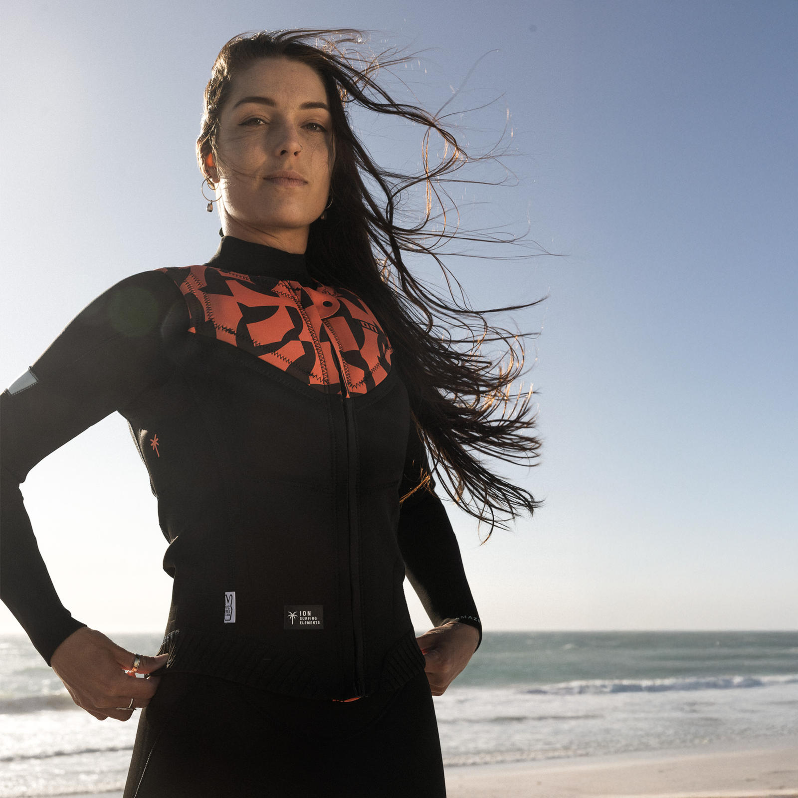 ION Ivy Impactweste Damen Front-Zip in schwarz und koralle beim Kitesurfen am Strand