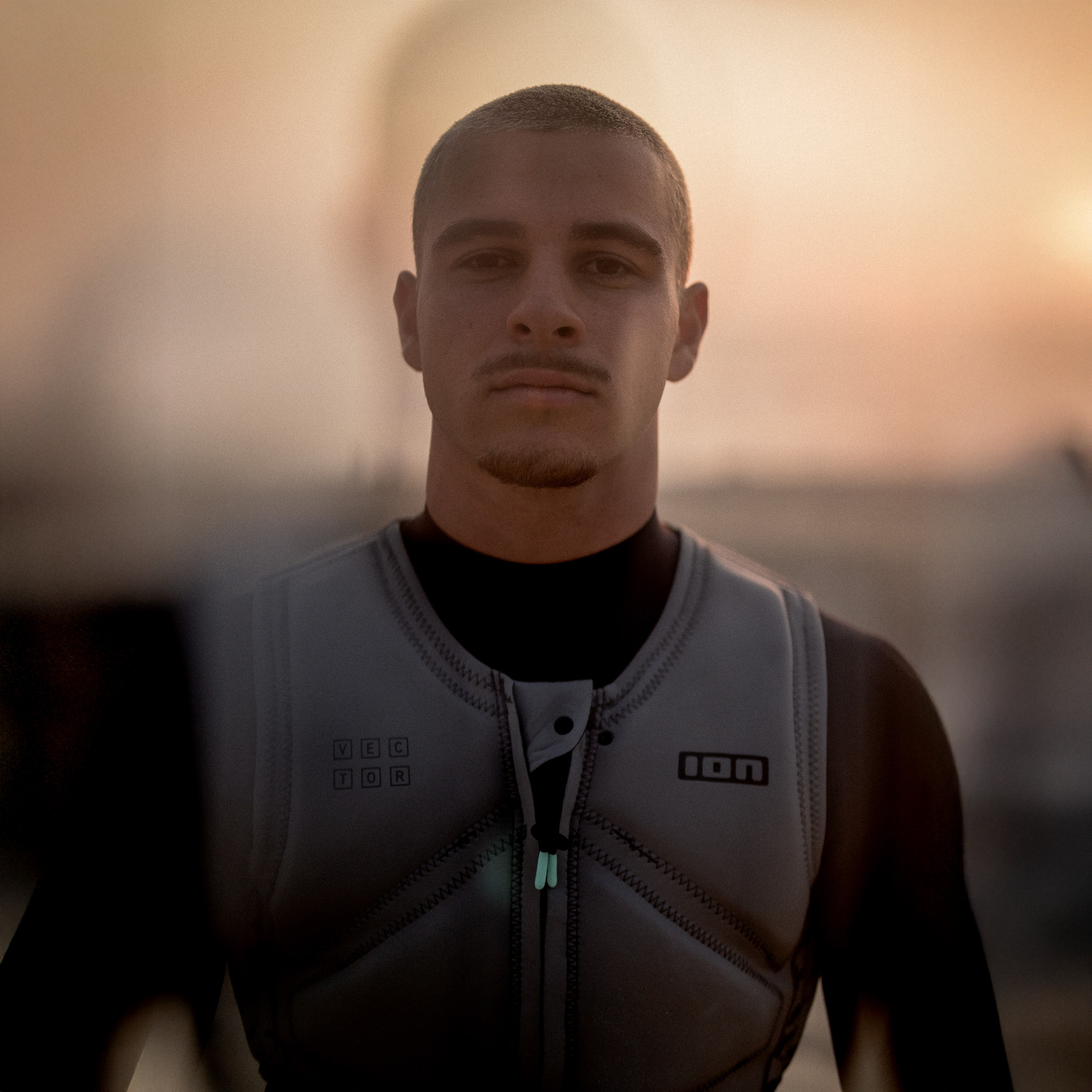 ION Vector men's front-zip impact vest in sage grey worn during kiteboarding at the coast