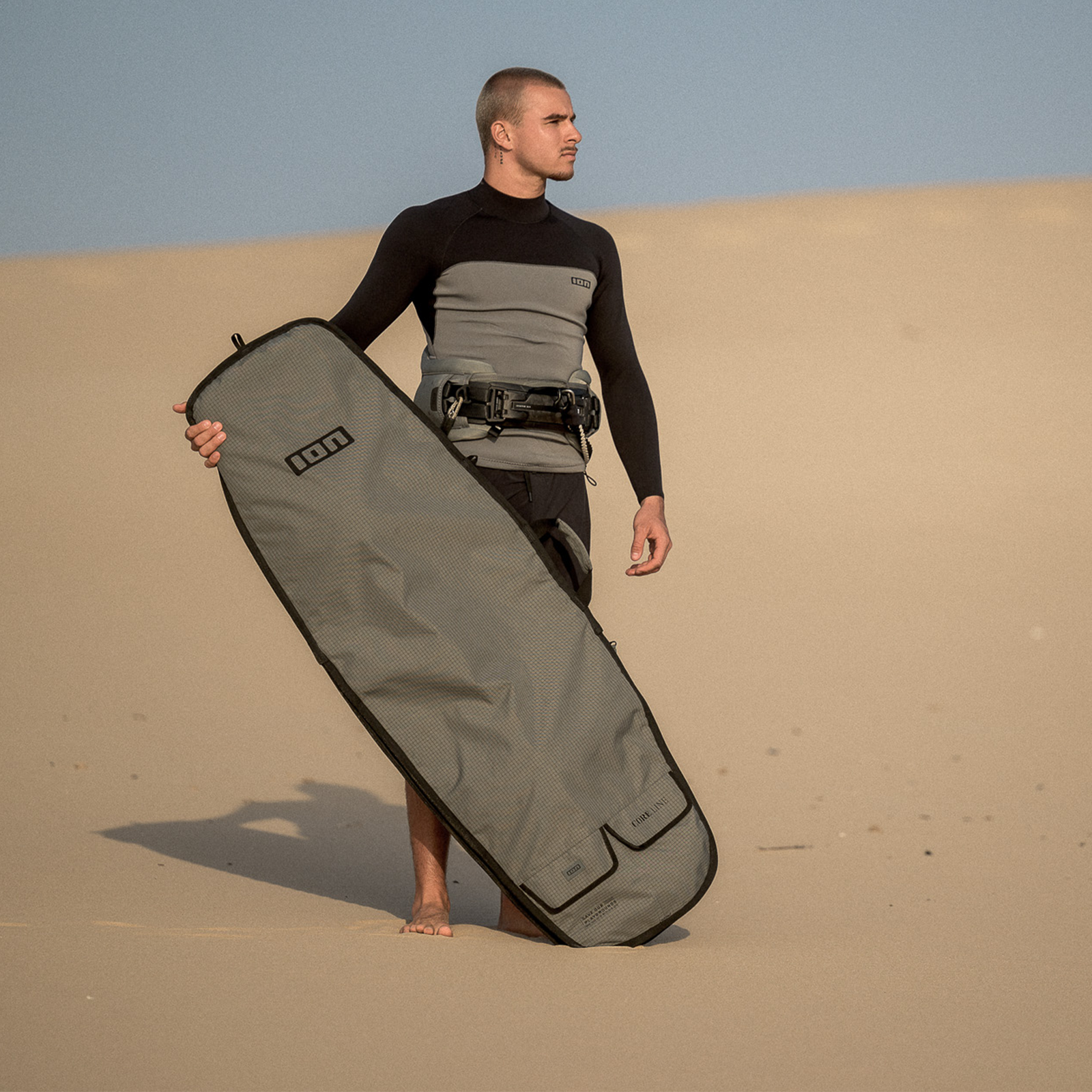 ION Twintip Boardbag Core in olive grey carried during kiteboarding at sand dunes