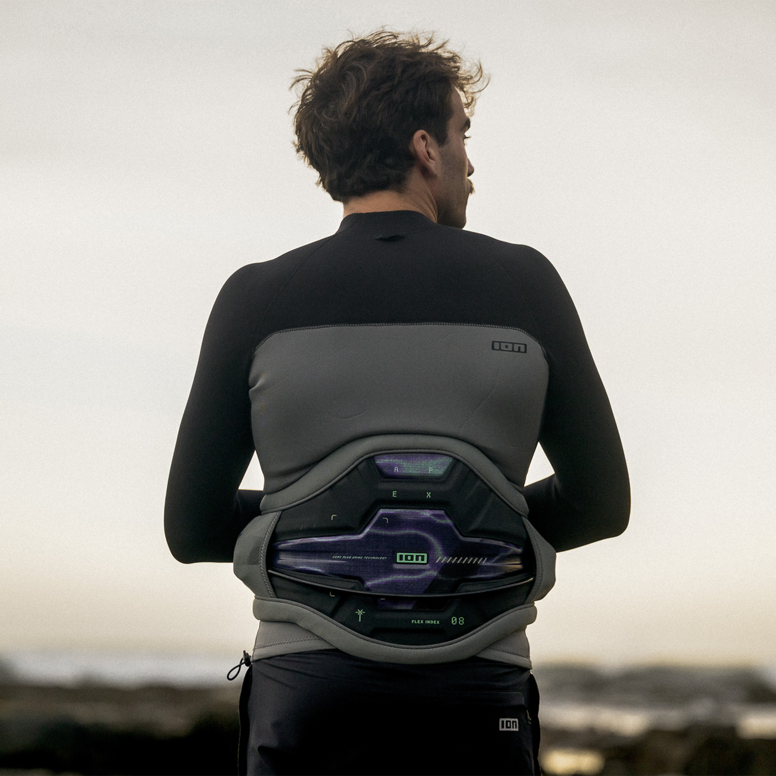 ION Apex waist harness in charcoal and sage grey with Ergo Pad lumbar support during kitesurfing at the coast