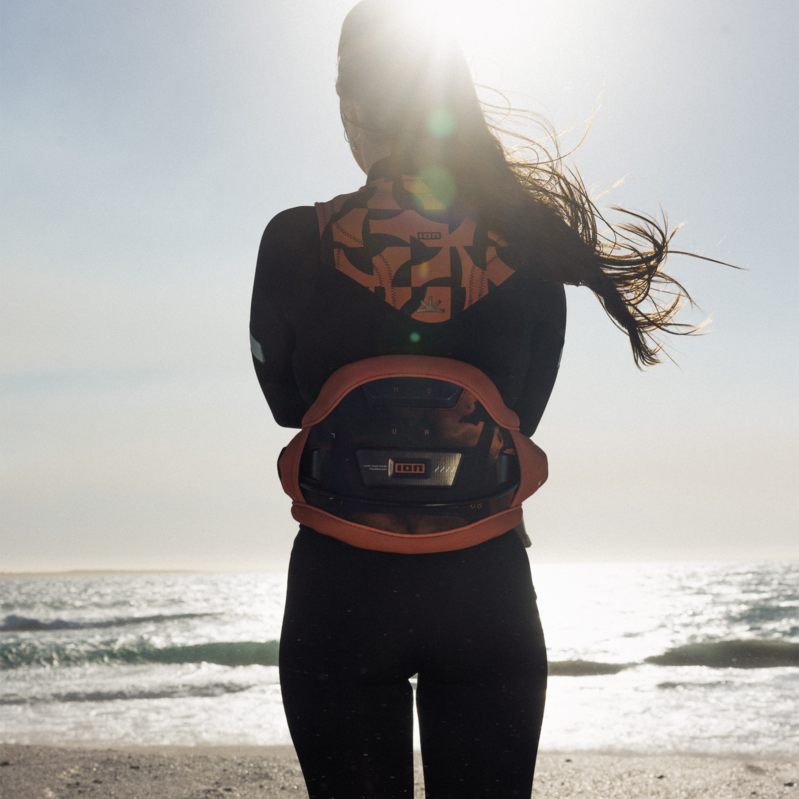 ION Nova waist harness in tiger coral during kitesurfing at the beach with Ergo Pad back support