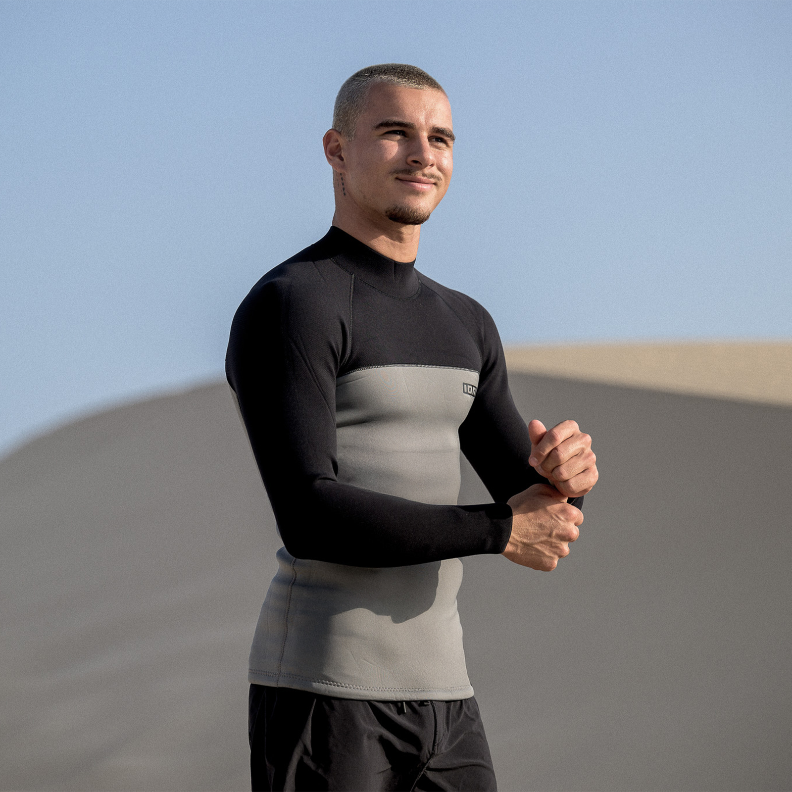 ION Neo Top 2/2 LS men's neoprene top in black and sage grey worn on sandy dunes