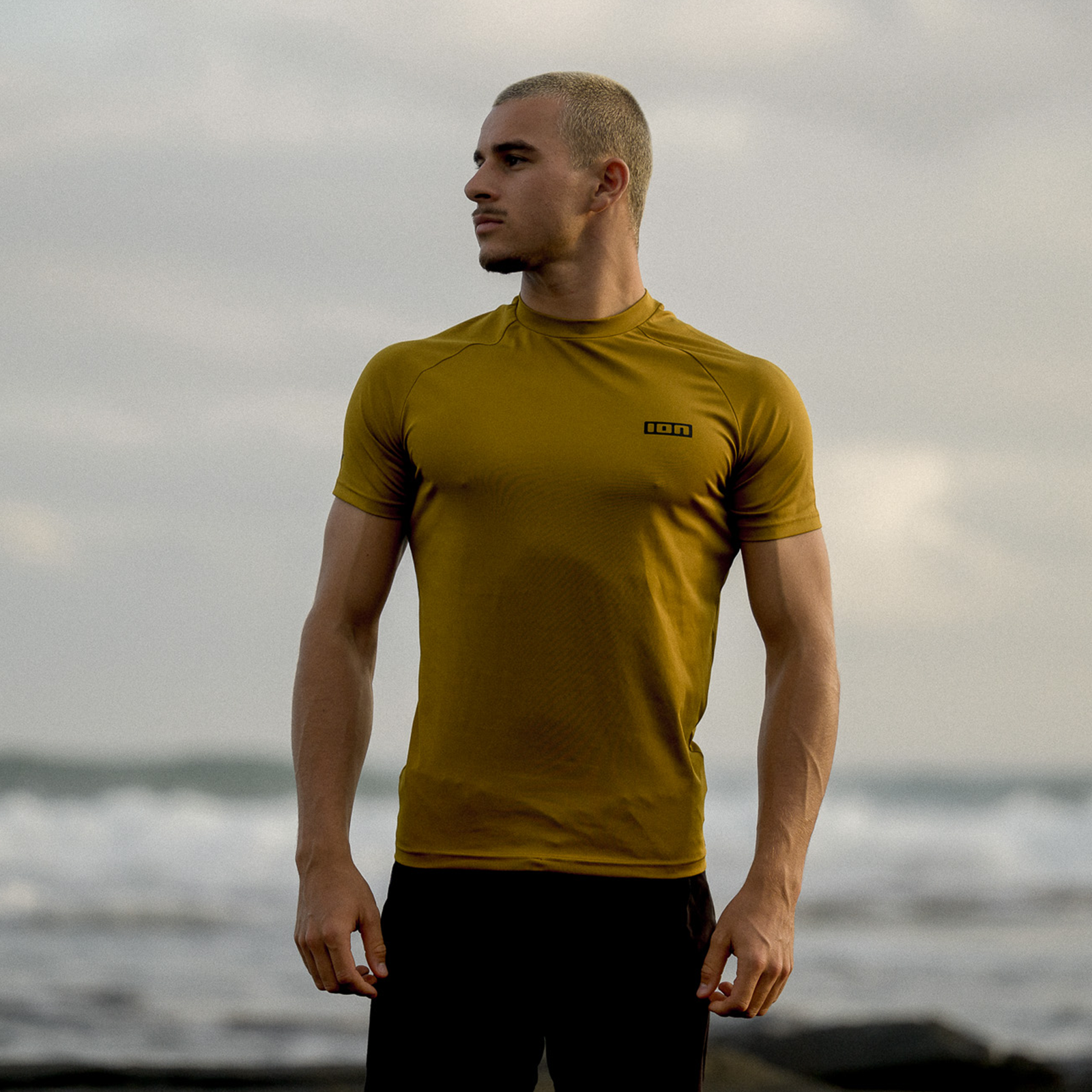 ION Rashguard SS homme top manches courtes en gold burst porté sur une côte rocheuse