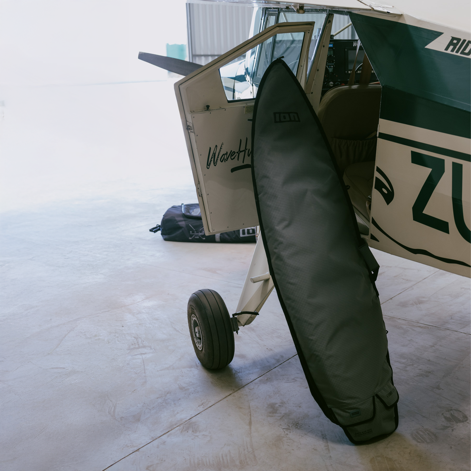 ION Core surf boardbag in dark charcoal during travel at an airfield hangar