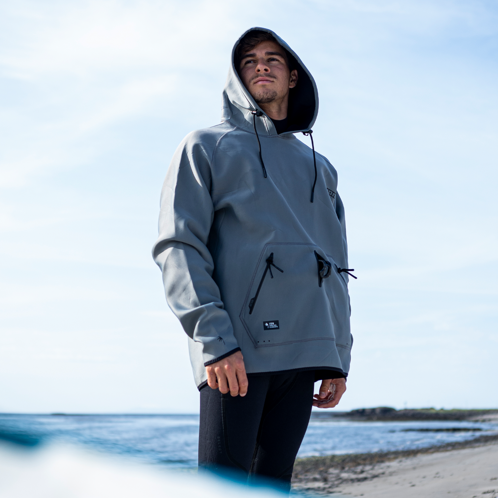 ION Neo Hoody Lite men neoprene hoodie in slate grey worn on the beach