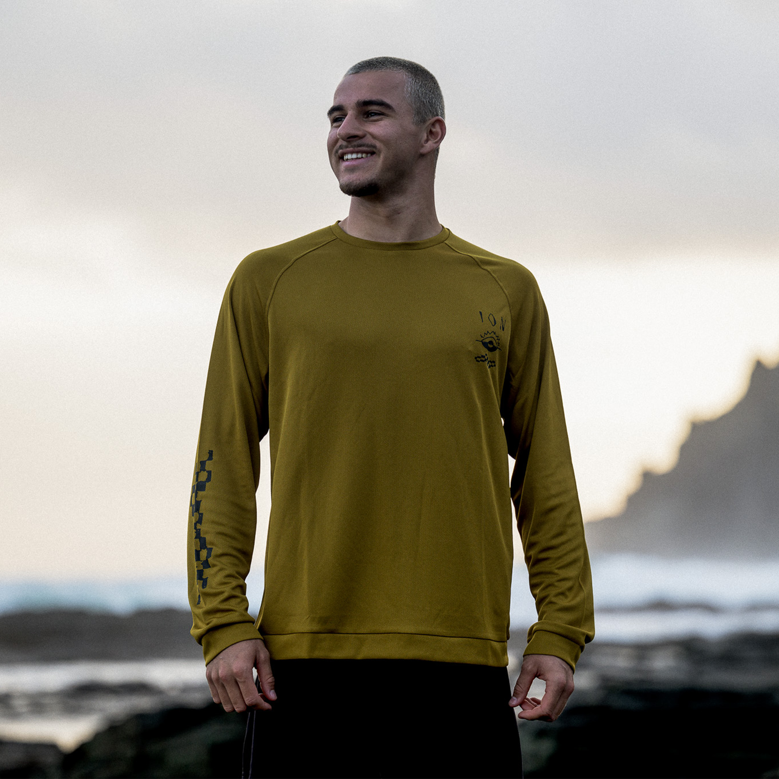 ION Water Wetshirt LS homme t-shirt manches longues sports nautiques en doré olive porté sur côte rocheuse