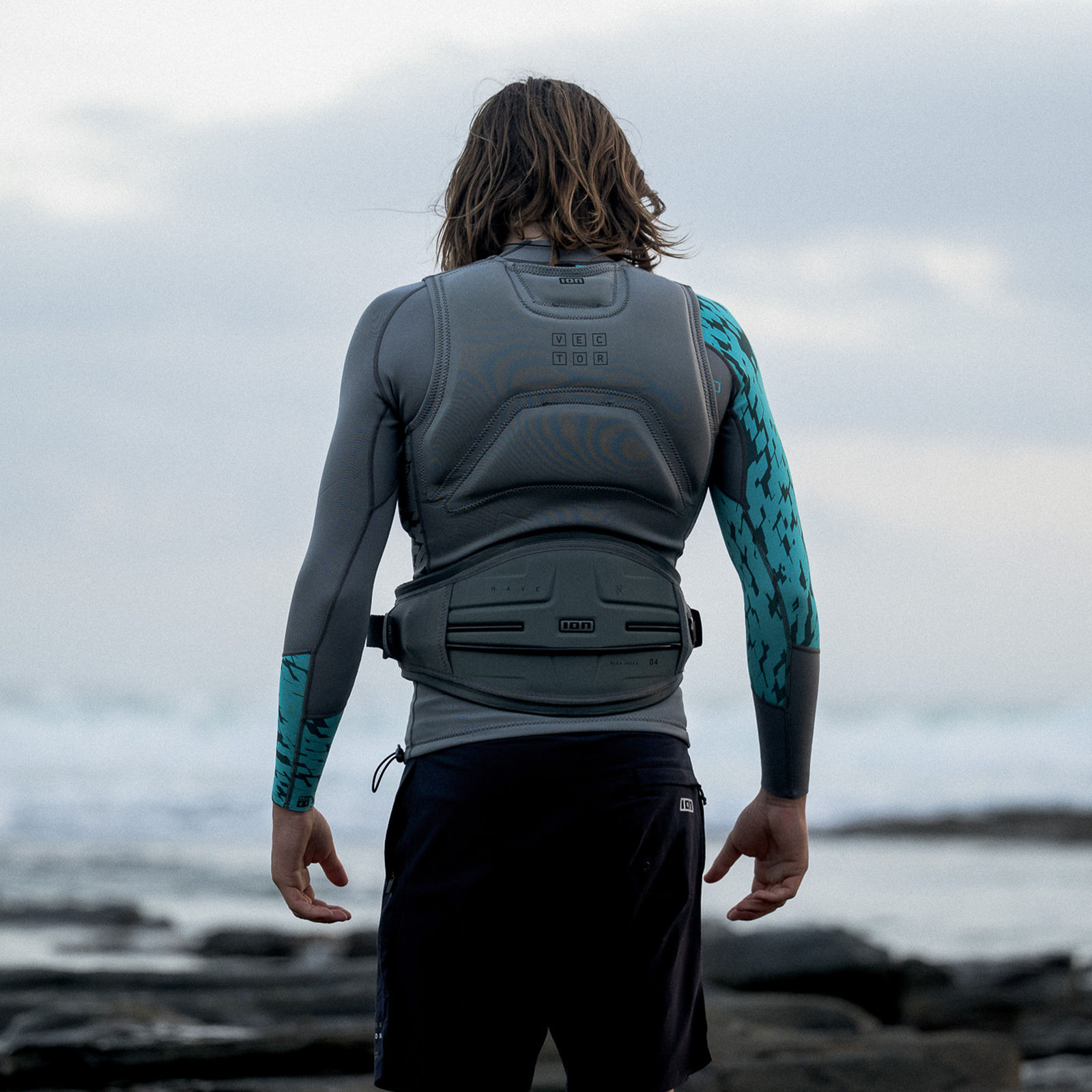 ION Rave waist harness in sage grey with soft-shell back plate during wing foiling at the coast