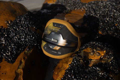 Harnais de taille ION Apex en noir et or avec Spectre Bar 2 et Ergo Pad sur rochers côtiers