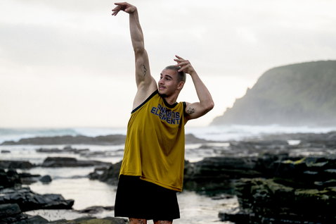 Wetshirt basketball ION Elements homme en jaune avec panneaux noirs en pose sur la côte rocheuse