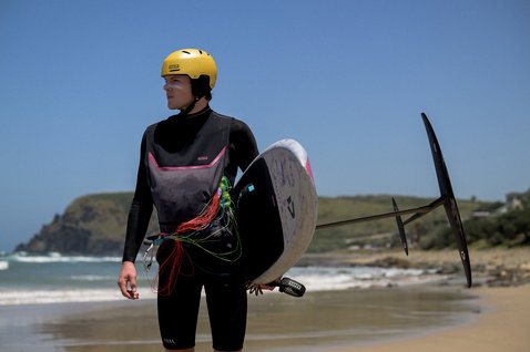 ION Neo Jam combinaison néoprène intégrale en noir et rose lors du wing foiling sur la plage