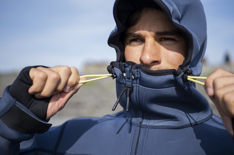ION Neo Shelter Jacket Amp homme veste en néoprène bleu ardoise à capuche ajustable lors d'une session kitesurf en Islande