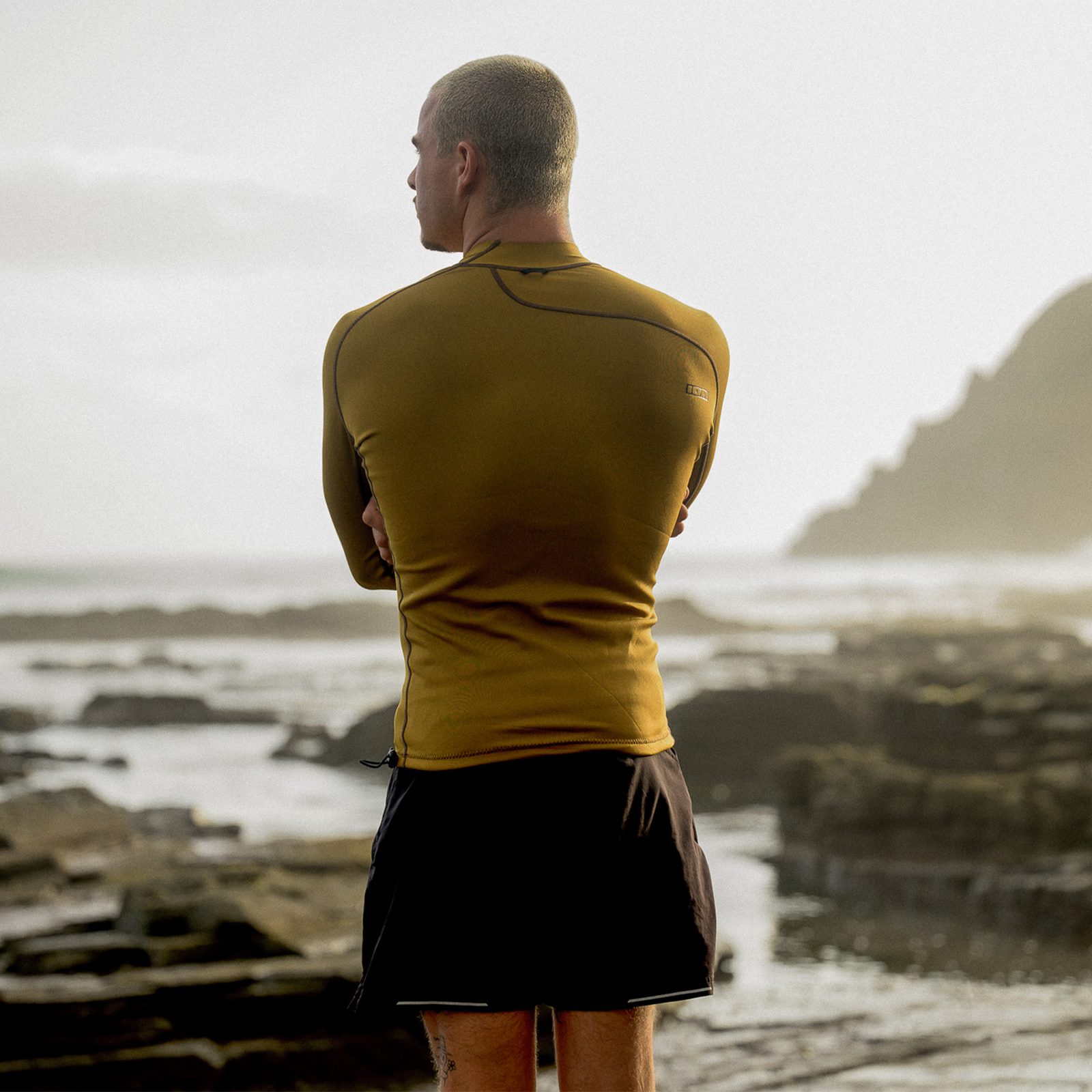 ION Neo Top 0.5 LS men neoprene top in gold burst worn at a rocky coastline