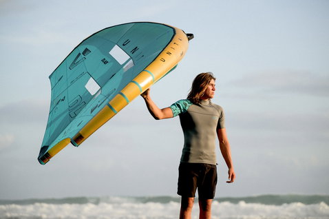 ION Neo Top 2/2 top de neoprene manga curta homem durante wing foiling no oceano em verde oliva escuro