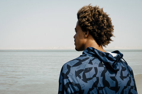 ION Water Wetshirt Hood LS Herren Langarm-Kapuzenshirt in dunkelblau mit Fischmuster beim Kitesurfen am Meer
