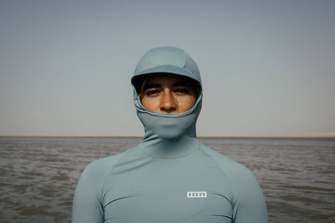 ION Sun Pro LS Rashguard Damen mit integrierter Kapuze und Gesichtsmaske in stahlblau an der Küste