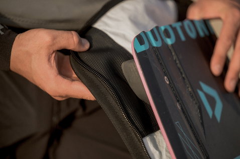 ION Core twintip board bag zipper opening detail in black, shown during kiteboard packing