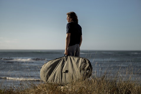 ION Wing Boardbag Core board bag in olive khaki held at the coast during wing foiling