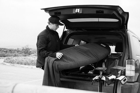 ION Wing Sock Slim Stretch-Boardcover 6'0" in dunkelgrau beim Verstauen im Auto an der Küste