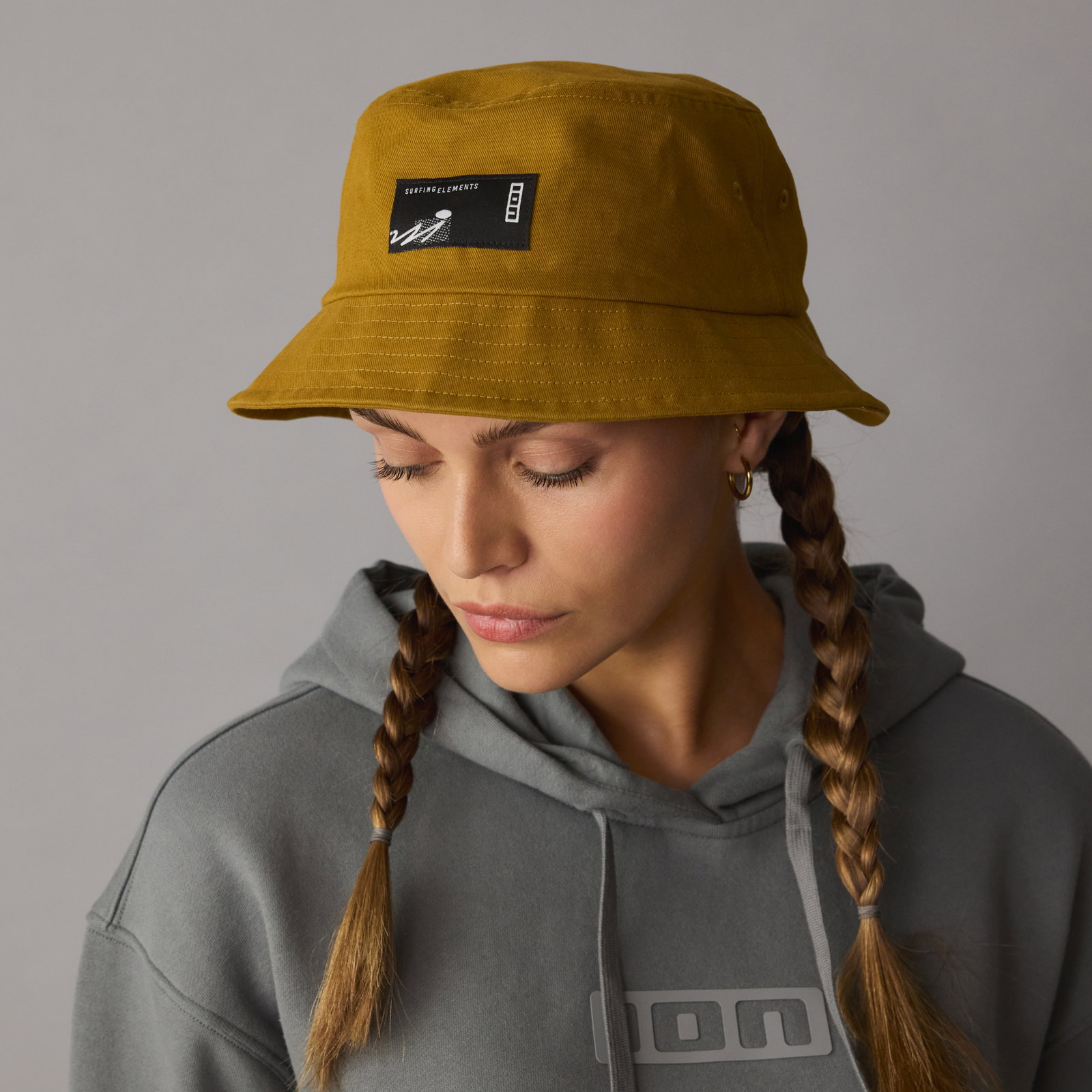 ION Cotton Bucket Hat in gold burst worn by a model in a studio setting