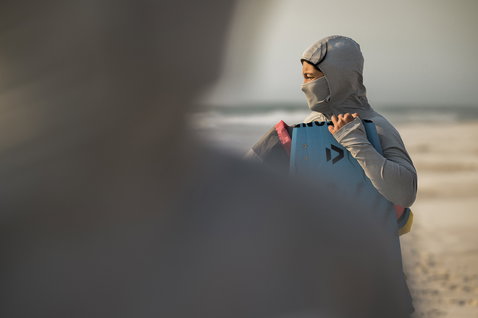 ION Storm Pro Langarm-Wetshirt Damen mit integrierter Kapuze in hellgrau beim Kitesurfen am Strand