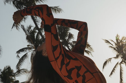 ION Amaze Hot Shorty 1,5mm Frontzip Langarm-Shorty in burnt orange mit schwarzem Print beim Wellenreiten