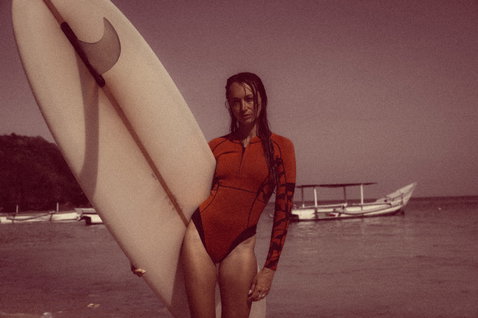 ION Amaze Hot Shorty 1,5mm Langarm-Frontzip-Shorty beim Wellenreiten an einem Tropenstrand in terrakotta