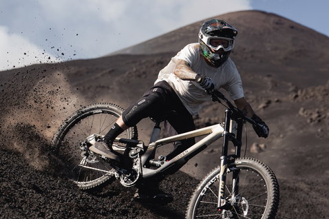 ION K-Pact knee pads in black during aggressive mountain biking on volcanic terrain