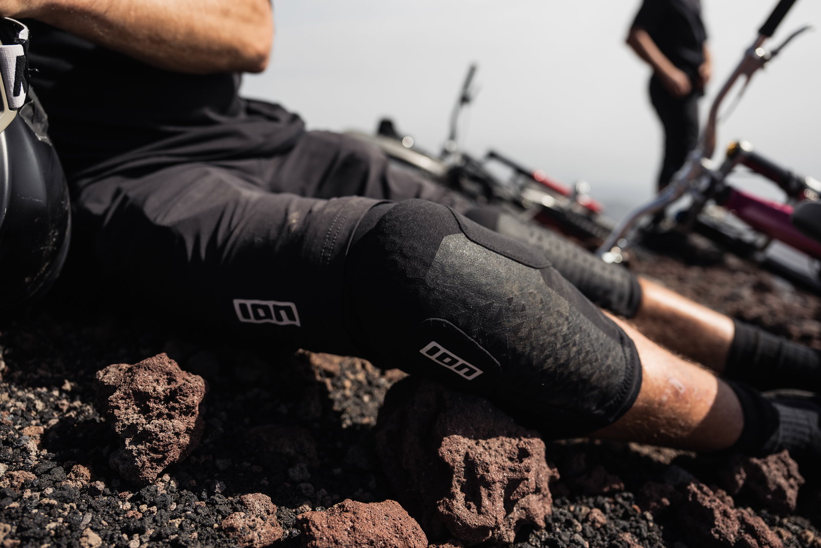 ION K-Pact knee pads in black during mountain biking on volcanic rocky terrain